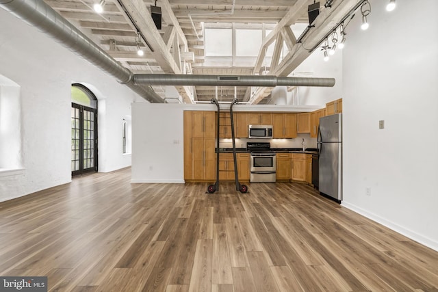 374 Shurs Ln Unit 304, Philadelphia, PA 19128 - kitchen with stainless steel appliances, a towering ceiling, dark countertops, wood finished floors, and rail lighting
