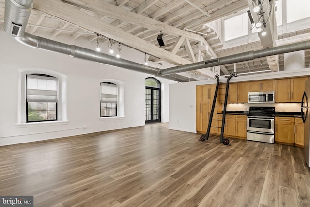 374 Shurs Ln Unit 304, Philadelphia, PA 19128 - kitchen with stainless steel appliances, open floor plan, dark countertops, high vaulted ceiling, and track lighting