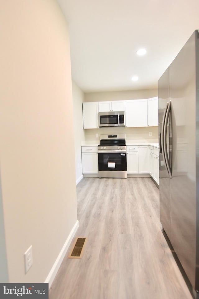 307 4th St, Seaford, DE 19973 - kitchen with appliances with stainless steel finishes, white cabinetry, light wood-type flooring, baseboards, and light countertops