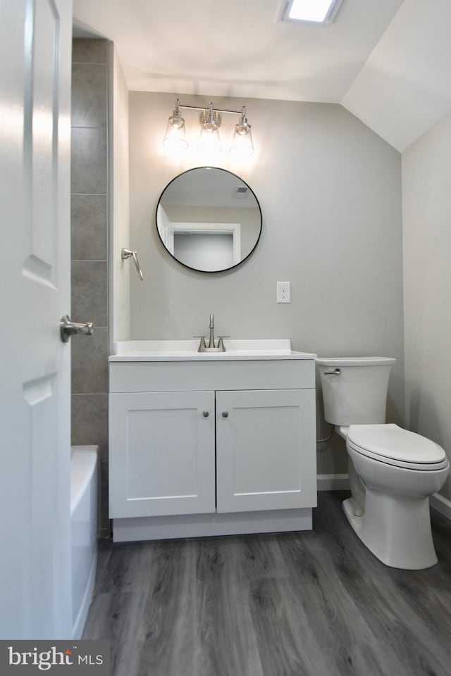 307 4th St, Seaford, DE 19973 - bathroom with vanity, wood finished floors, toilet, a bath, and lofted ceiling