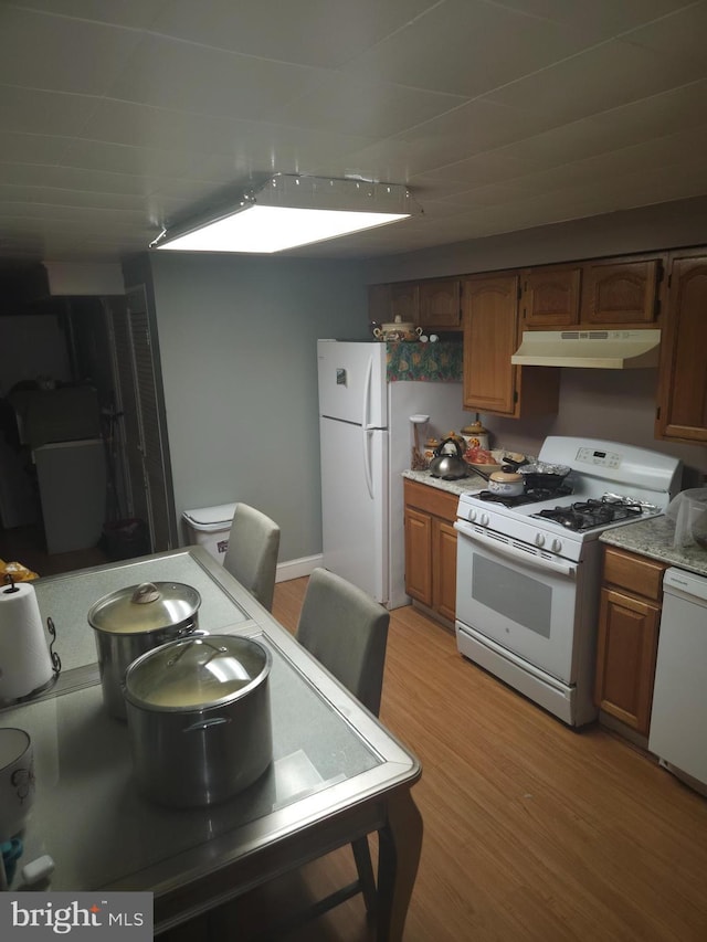 421 Folcroft St, Baltimore, MD 21224 - kitchen with white appliances, under cabinet range hood, light countertops, light wood-type flooring, and brown cabinetry