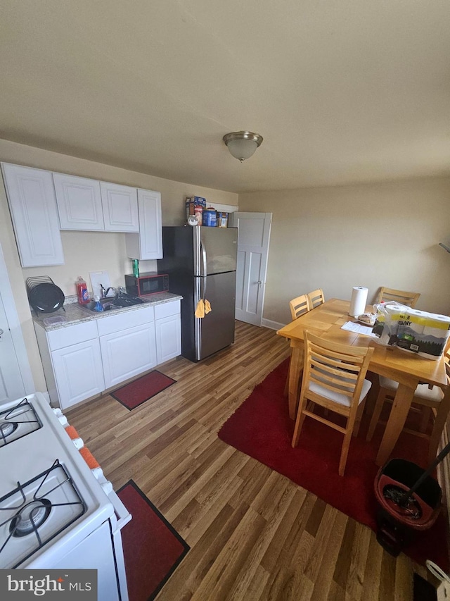 421 Folcroft St, Baltimore, MD 21224 - kitchen featuring freestanding refrigerator, white gas range, white cabinetry, light wood finished floors, and a sink