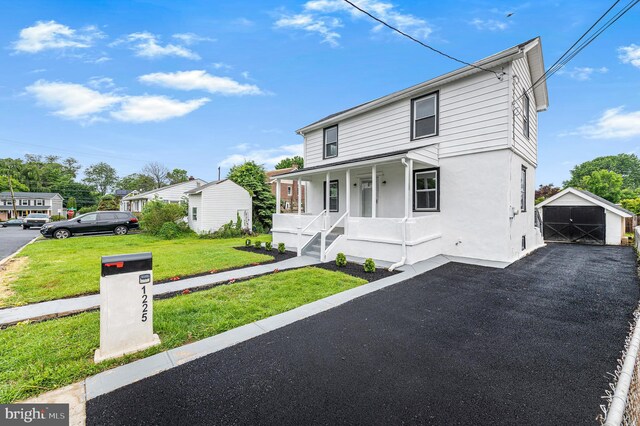 1225 Harper Ave, Woodlyn, PA 19094 - view of front of house featuring covered porch, a front lawn, stucco siding, a detached garage, and an outbuilding