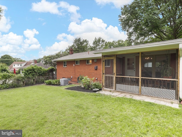 905 Peele Pl, Alexandria, VA 22304 - rear view of property featuring central air condition unit, a sunroom, brick siding, a lawn, and a chimney