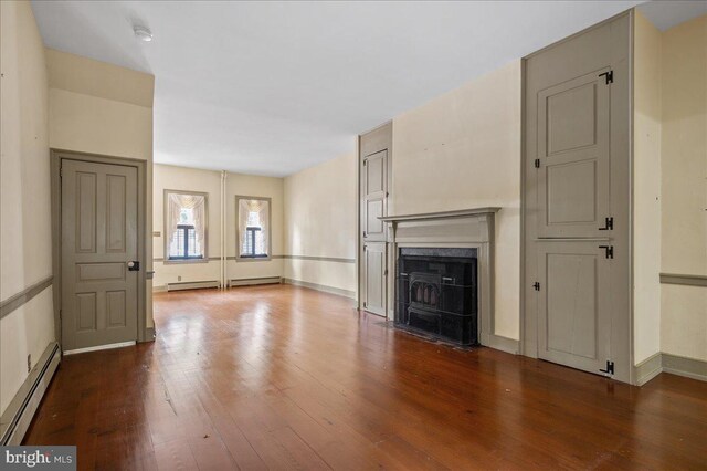 28 The Strand, New Castle, DE 19720 - unfurnished living room featuring a baseboard radiator, dark wood-style flooring, a fireplace with flush hearth, and baseboards