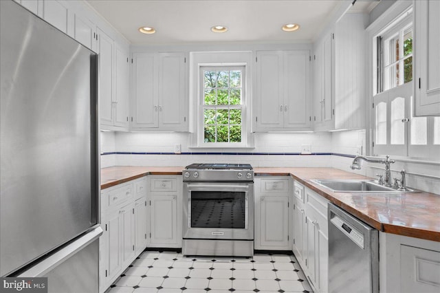 28 The Strand, New Castle, DE 19720 - kitchen featuring stainless steel appliances, a sink, light floors, white cabinetry, and decorative backsplash