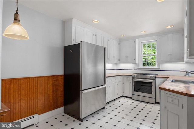 28 The Strand, New Castle, DE 19720 - kitchen featuring appliances with stainless steel finishes, a baseboard heating unit, a sink, light floors, and white cabinetry