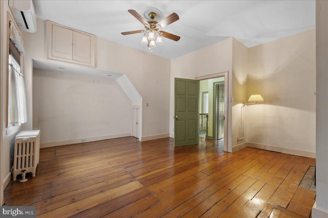 28 The Strand, New Castle, DE 19720 - unfurnished living room featuring radiator heating unit, an AC wall unit, light wood-style flooring, a ceiling fan, and baseboards