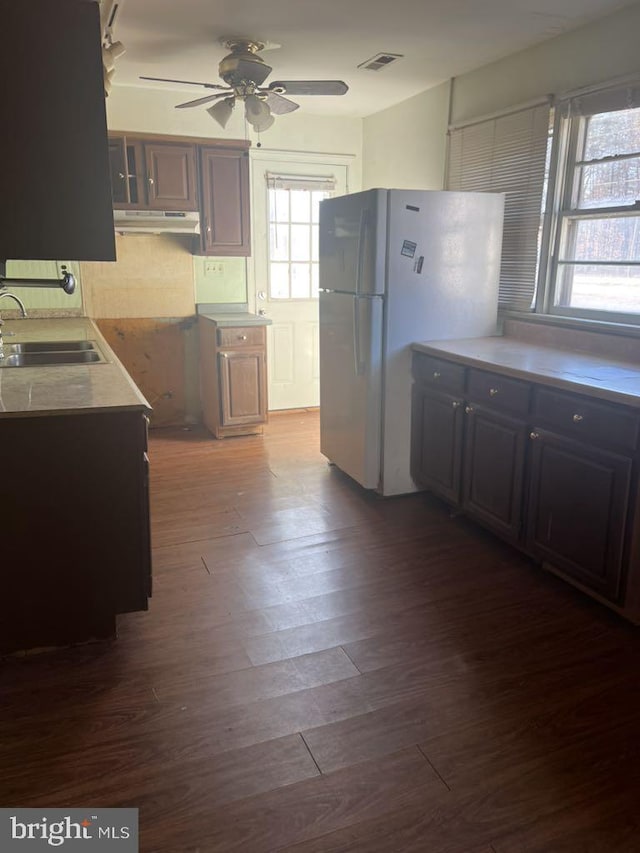 6640 Pomfret Rd, La Plata, MD 20646 - kitchen featuring a sink, under cabinet range hood, a ceiling fan, freestanding refrigerator, and dark wood-style flooring
