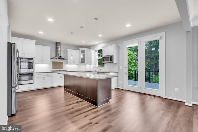 40578 Sculpin Ct, Aldie, VA 20105 - kitchen featuring wall chimney range hood, stainless steel appliances, tasteful backsplash, wood finished floors, and recessed lighting