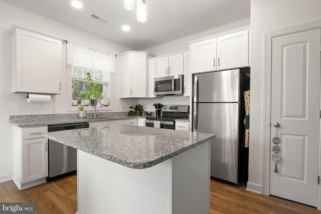 12 Parkview Dr, Carlisle, PA 17013 - kitchen featuring appliances with stainless steel finishes, white cabinetry, dark wood-style flooring, a kitchen island, and light stone countertops