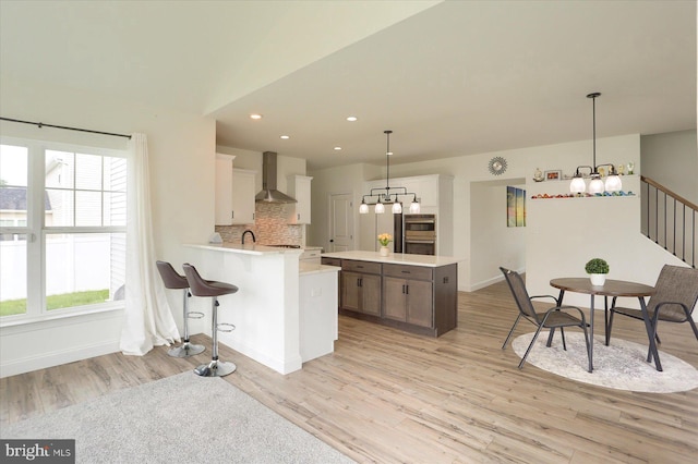 6300 Neha Dr Unit 32, Mechanicsburg, PA 17050 - kitchen featuring a chandelier, wall chimney range hood, light wood-style flooring, light countertops, and stainless steel double oven