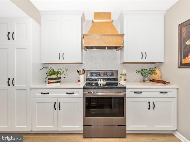 41 E Frederick St, Williamsport, MD 21795 - kitchen with stainless steel range with electric stovetop, custom exhaust hood, light countertops, backsplash, and white cabinetry