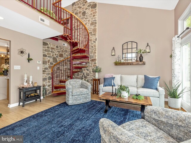 41 E Frederick St, Williamsport, MD 21795 - living room featuring wood finished floors, a high ceiling, stairs, a stone fireplace, and baseboards