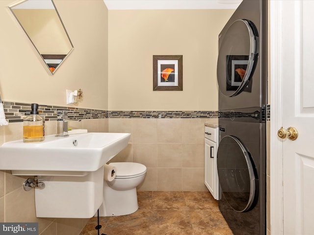 41 E Frederick St, Williamsport, MD 21795 - bathroom featuring stacked washing machine and dryer, tile walls, toilet, and a wainscoted wall
