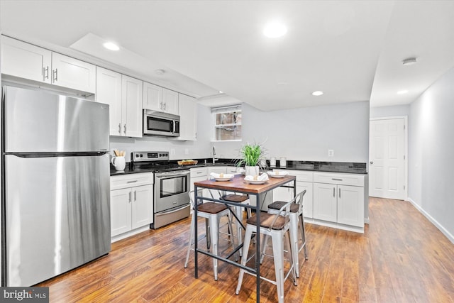 121 V St NW, Washington, DC 20001 - kitchen featuring stainless steel appliances, dark countertops, recessed lighting, white cabinetry, and wood finished floors