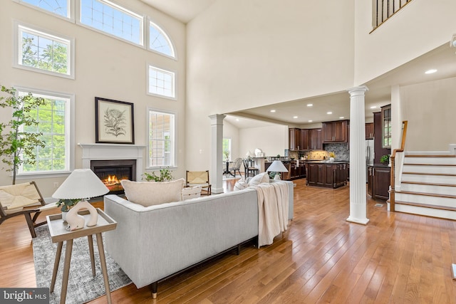 4403 Cedar Reach Ln, Bowie, MD 20720 - living room featuring ornate columns, a glass covered fireplace, light wood-type flooring, a towering ceiling, and stairway