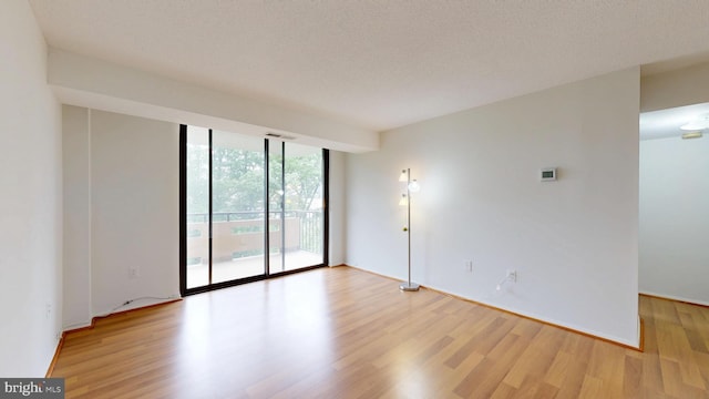 1808 Old Meadow Rd Unit 1015, Mclean, VA 22102 - empty room featuring wood finished floors, a wall of windows, a textured ceiling, and baseboards