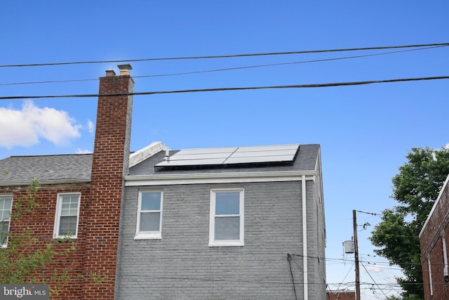 5054 8th St NE, Washington, DC 20017 - view of home's exterior featuring brick siding, a chimney, and solar panels