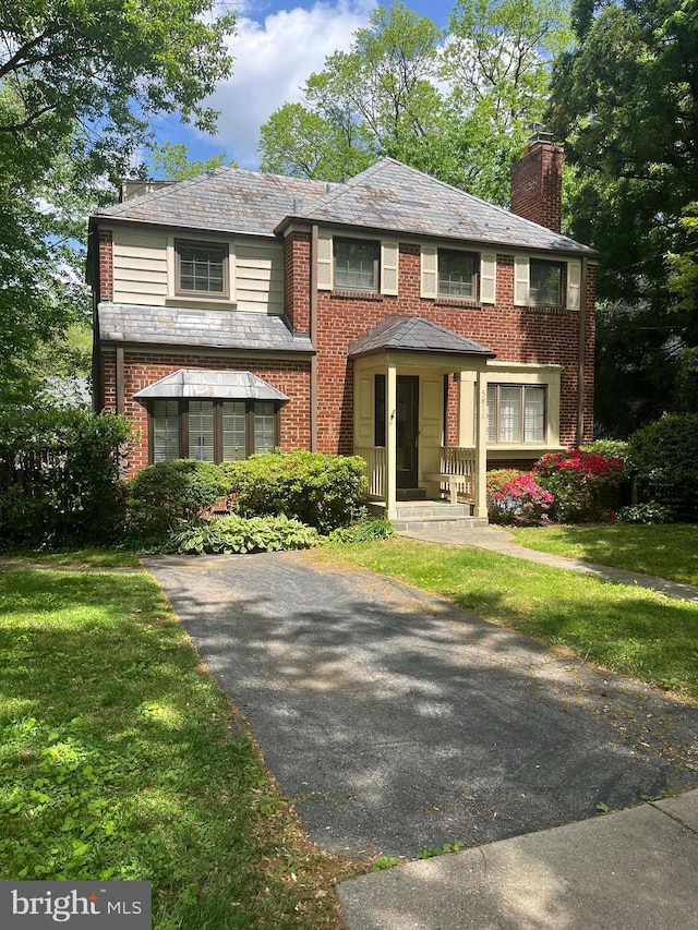 5811 Augusta Ln, Bethesda, MD 20816 - view of front of house featuring a high end roof, a chimney, a front yard, and brick siding