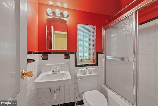 5811 Augusta Ln, Bethesda, MD 20816 - bathroom featuring toilet, shower / bath combination with glass door, wainscoting, tile walls, and a sink
