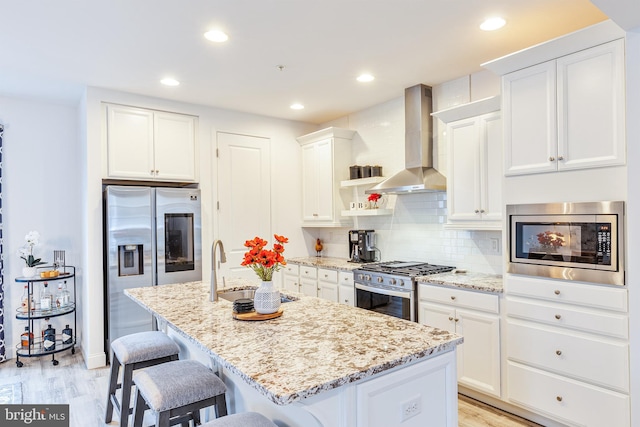 3226 Light Way, Mechanicsburg, PA 17055 - kitchen featuring appliances with stainless steel finishes, wall chimney exhaust hood, a breakfast bar, white cabinetry, and a kitchen island with sink