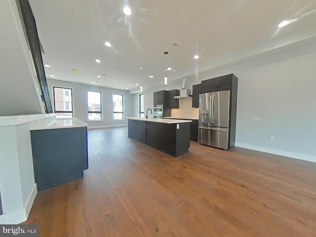 3143 W Montgomery Ave, Philadelphia, PA 19121 - kitchen featuring appliances with stainless steel finishes, open floor plan, a center island with sink, light countertops, and wood finished floors