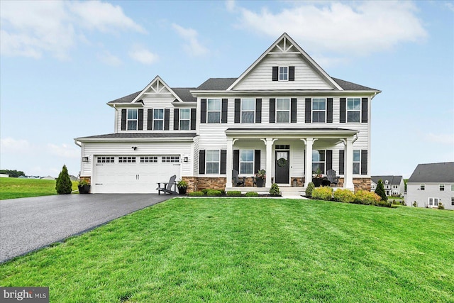 48 Winifred Dr, Hanover, PA 17331 - view of front of property with covered porch, driveway, an attached garage, stone siding, and a front lawn