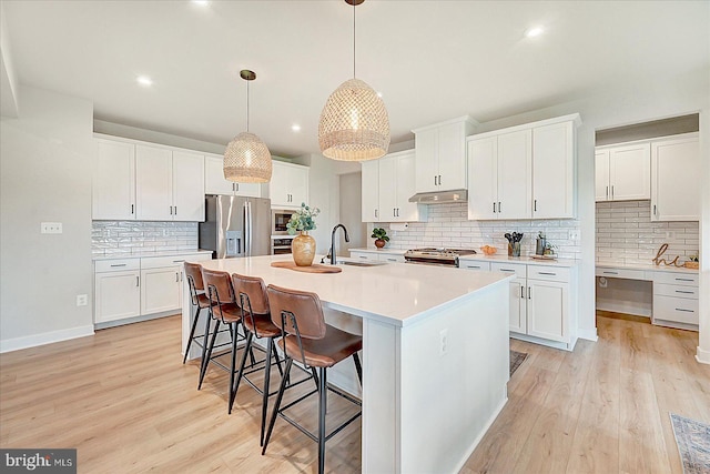 48 Winifred Dr, Hanover, PA 17331 - kitchen featuring appliances with stainless steel finishes, a sink, under cabinet range hood, backsplash, and light wood finished floors