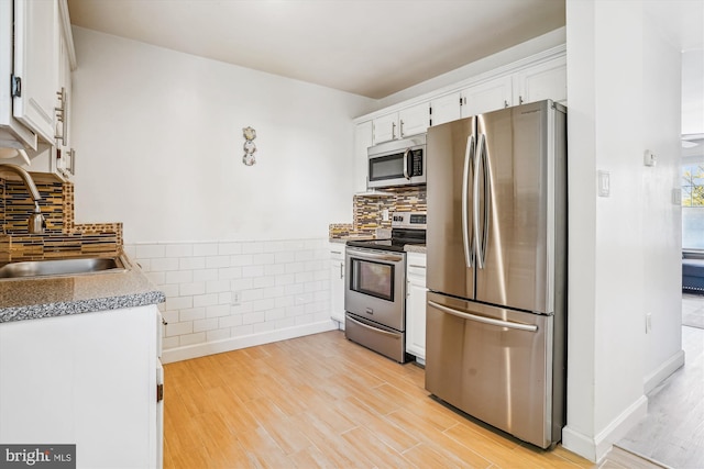 2557 Peter Jefferson Ln, Herndon, VA 20171 - kitchen with appliances with stainless steel finishes, a sink, light wood-type flooring, white cabinetry, and tile walls