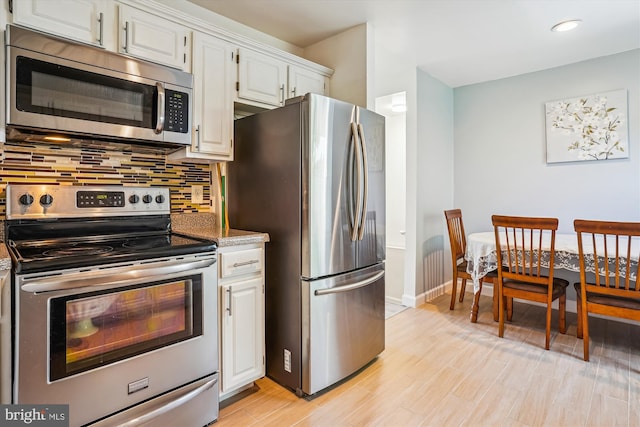 2557 Peter Jefferson Ln, Herndon, VA 20171 - kitchen featuring appliances with stainless steel finishes, tasteful backsplash, baseboards, white cabinets, and light wood-style flooring