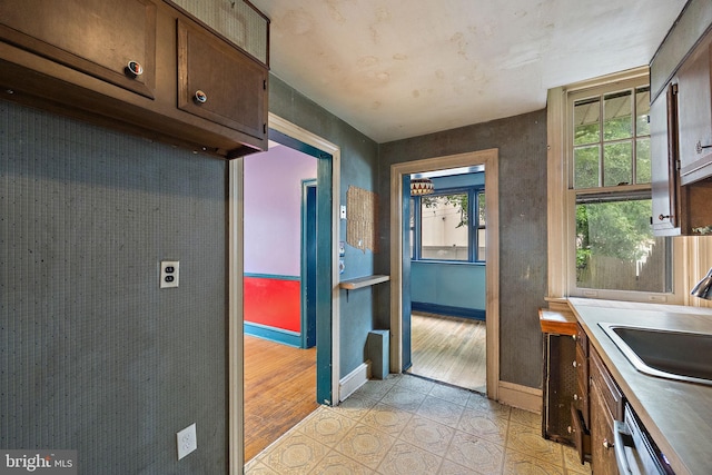 907 W Twenty Fifth St, Wilmington, DE 19802 - kitchen with stainless steel dishwasher, a sink, baseboards, light tile patterned flooring, and dark brown cabinets