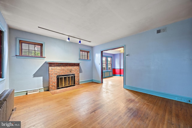 907 W Twenty Fifth St, Wilmington, DE 19802 - unfurnished living room with radiator, a fireplace, hardwood / wood-style floors, and plenty of natural light