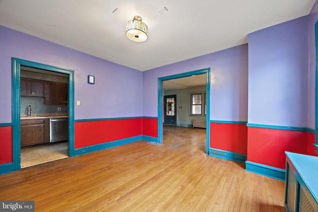907 W Twenty Fifth St, Wilmington, DE 19802 - unfurnished room featuring radiator heating unit, light wood-style floors, baseboards, and a sink