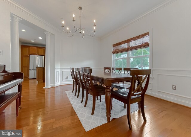 24655 Broad Creek Dr, Hollywood, MD 20636 - dining space featuring ornate columns, crown molding, a decorative wall, a chandelier, and light wood finished floors