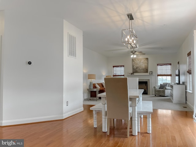24655 Broad Creek Dr, Hollywood, MD 20636 - dining area with a ceiling fan, light wood-style floors, baseboards, a fireplace, and a chandelier