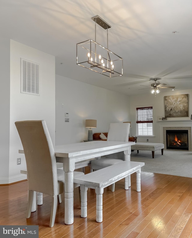 24655 Broad Creek Dr, Hollywood, MD 20636 - dining room featuring a ceiling fan, wood finished floors, a chandelier, and a warm lit fireplace