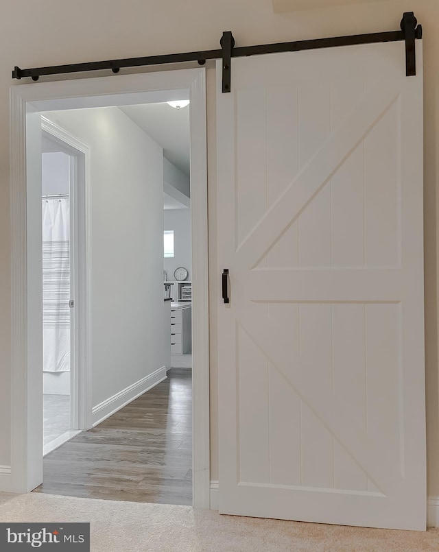 24655 Broad Creek Dr, Hollywood, MD 20636 - hall featuring a barn door, wood finished floors, and baseboards