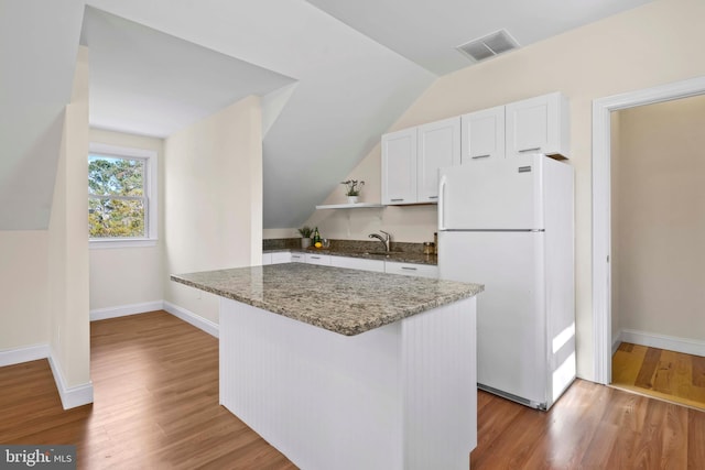 1109 Cherry Point Rd, West River, MD 20778 - kitchen featuring freestanding refrigerator, a sink, lofted ceiling, white cabinetry, and dark stone counters