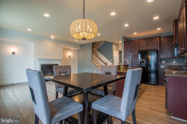 46 Tavern House Hl, Mechanicsburg, PA 17050 - dining space featuring stairs, a decorative wall, a chandelier, recessed lighting, and a glass covered fireplace
