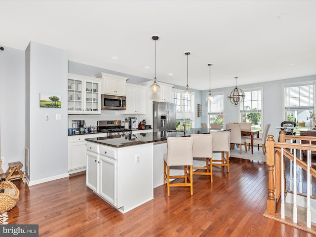 6540 Newton Dr, Frederick, MD 21703 - kitchen with stainless steel appliances, hardwood / wood-style floors, a kitchen island, white cabinetry, and a kitchen breakfast bar