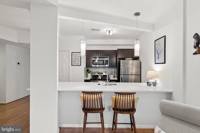 329 Rhode Island Ave NE Unit 104, Washington, DC 20002 - kitchen with appliances with stainless steel finishes, a peninsula, a sink, decorative backsplash, and light countertops