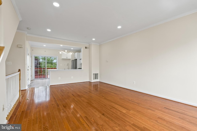42038 Angel Arch Ter, Aldie, VA 20105 - unfurnished living room featuring wood-type flooring, crown molding, baseboards, recessed lighting, and a sink