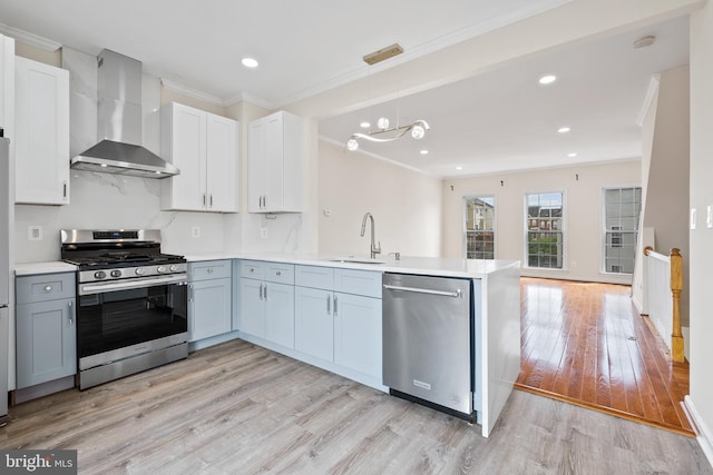 42038 Angel Arch Ter, Aldie, VA 20105 - kitchen featuring appliances with stainless steel finishes, wall chimney range hood, a sink, a peninsula, and ornamental molding