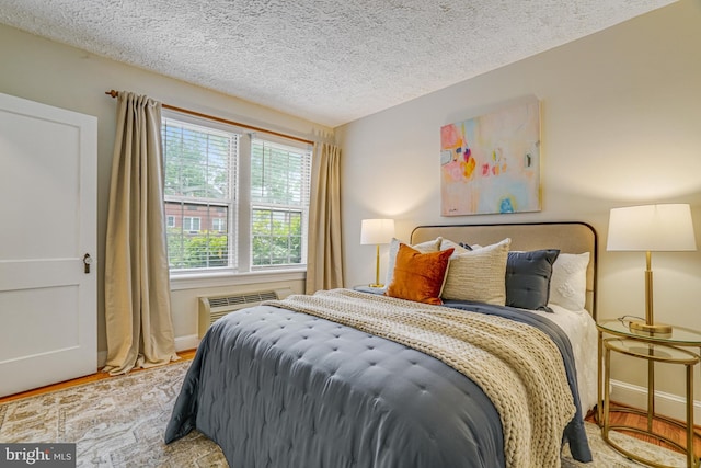 715 S Washington St Unit A-13, Alexandria, VA 22314 - bedroom featuring a wall mounted AC, a textured ceiling, baseboards, and wood finished floors