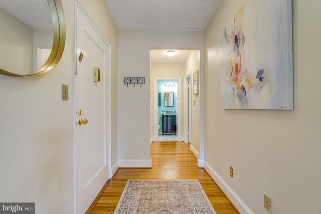 715 S Washington St Unit A-13, Alexandria, VA 22314 - corridor featuring a textured ceiling, light wood-style flooring, and baseboards