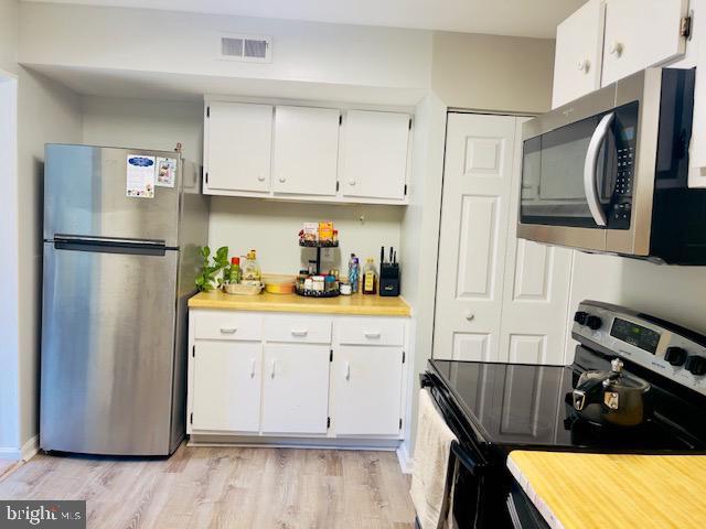 9707 Kings Crown Ct Unit 101, Fairfax, VA 22031 - kitchen with stainless steel appliances, white cabinets, light countertops, and light wood-type flooring