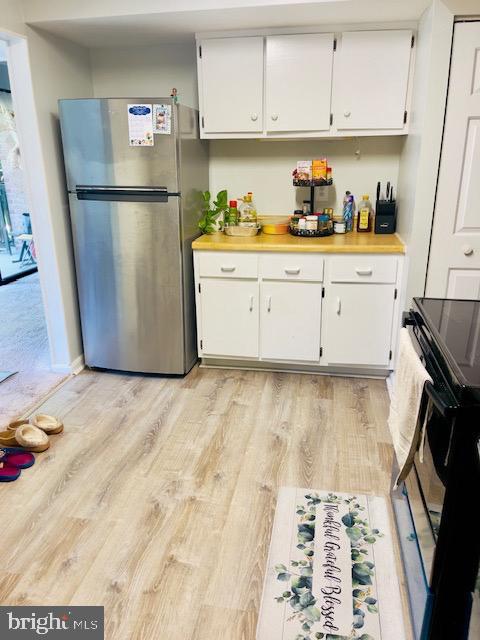 9707 Kings Crown Ct Unit 101, Fairfax, VA 22031 - kitchen featuring freestanding refrigerator, light wood-type flooring, range, and white cabinetry