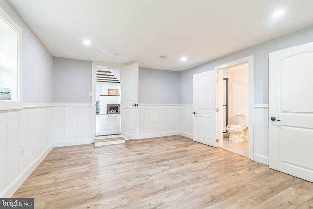 309 Bayview Rd, Edgewater, MD 21037 - unfurnished room featuring a fireplace, light wood-style flooring, wainscoting, recessed lighting, and a decorative wall
