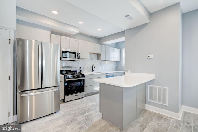 2915 Baker St, Baltimore, MD 21216 - kitchen featuring stainless steel appliances, a sink, light countertops, a peninsula, and decorative backsplash